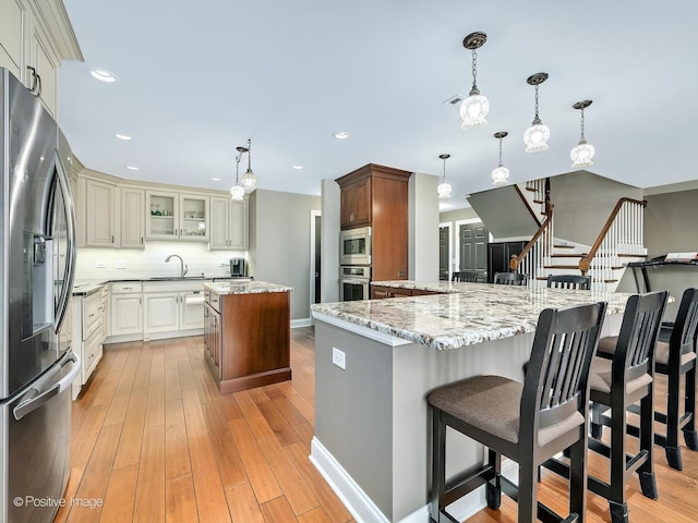 kitchen with light stone counters, decorative backsplash, stainless steel appliances, a sink, and a center island