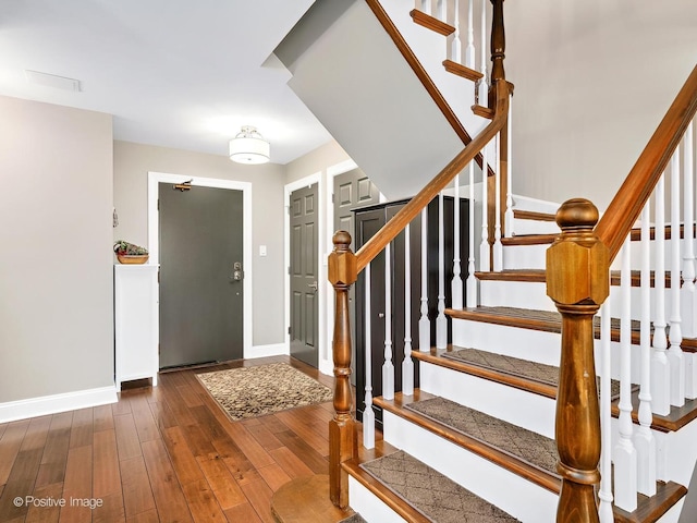 foyer entrance with baseboards, stairway, and hardwood / wood-style flooring