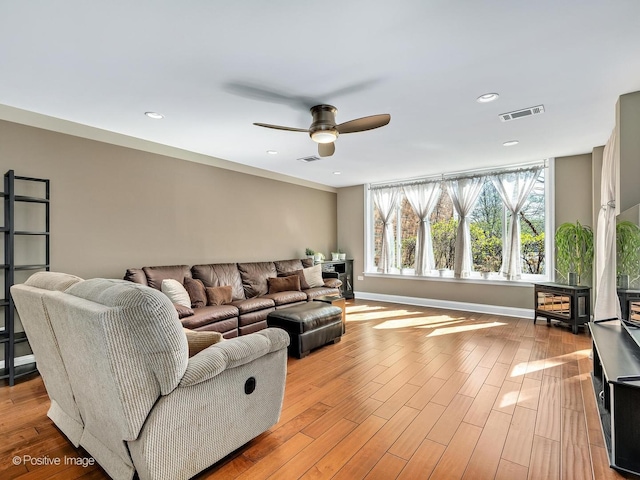 living room with visible vents, a ceiling fan, a wood stove, and recessed lighting