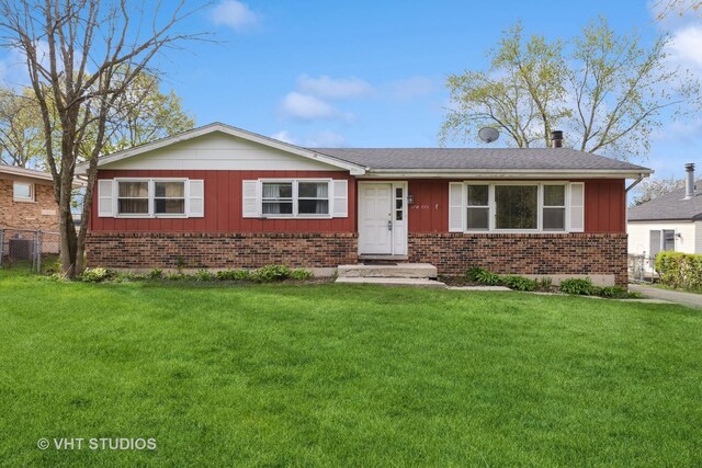 single story home featuring board and batten siding, brick siding, fence, and a front lawn