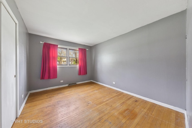 unfurnished bedroom with wood-type flooring, baseboards, visible vents, and a closet