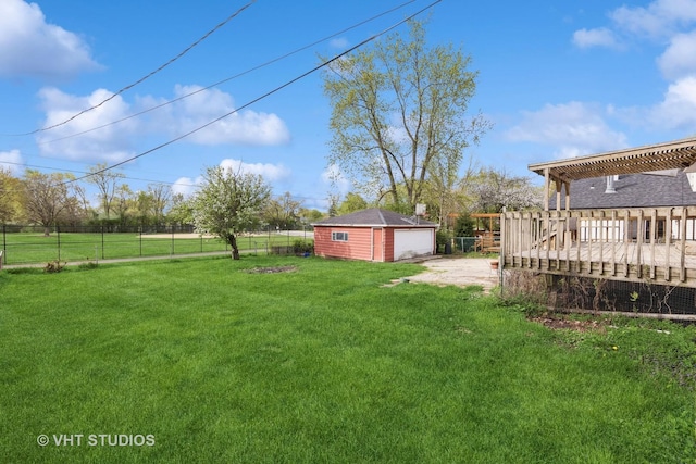 view of yard with driveway, a deck, an outbuilding, a garage, and fence