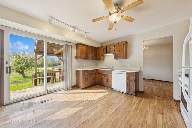 kitchen with a ceiling fan, a sink, light wood finished floors, under cabinet range hood, and white appliances