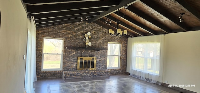 unfurnished living room featuring rail lighting, a fireplace, brick wall, and plenty of natural light