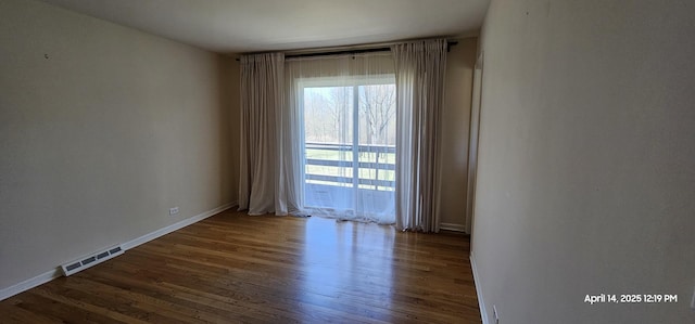 spare room with baseboards, wood finished floors, and visible vents