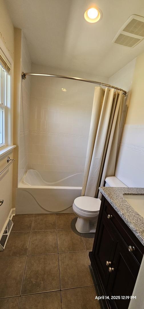 full bath featuring tile patterned flooring, visible vents, toilet, vanity, and shower / bath combo with shower curtain