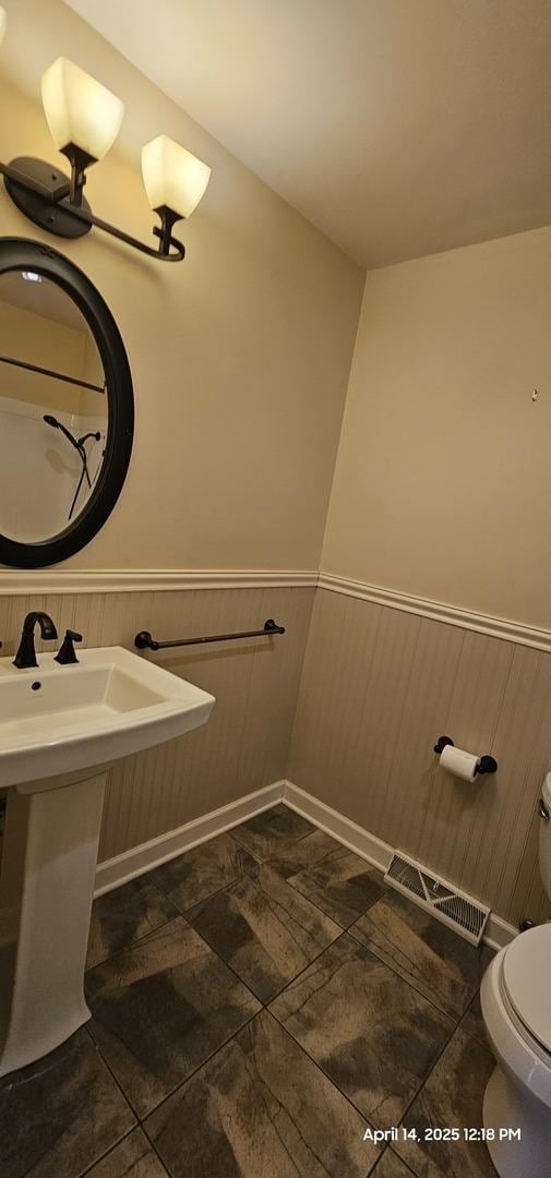 half bath featuring wainscoting, tile patterned floors, visible vents, and toilet
