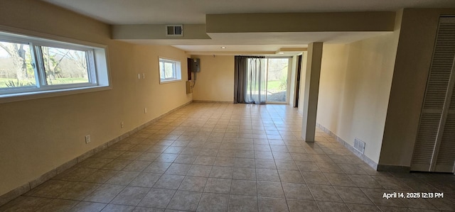 tiled empty room with baseboards and visible vents