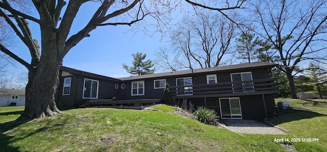 rear view of property featuring a wooden deck and a yard