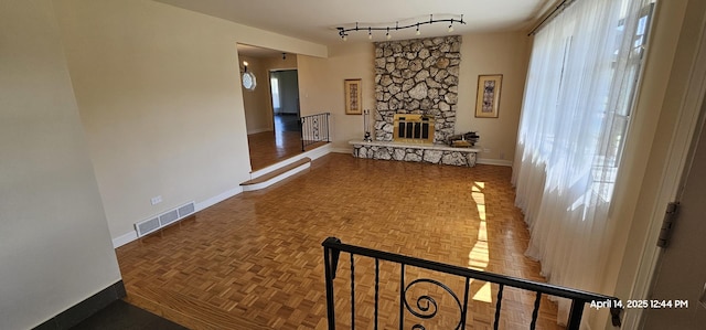 hall with track lighting, baseboards, and visible vents