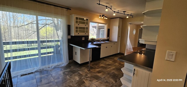 kitchen with white cabinets, dishwasher, visible vents, a sink, and glass insert cabinets