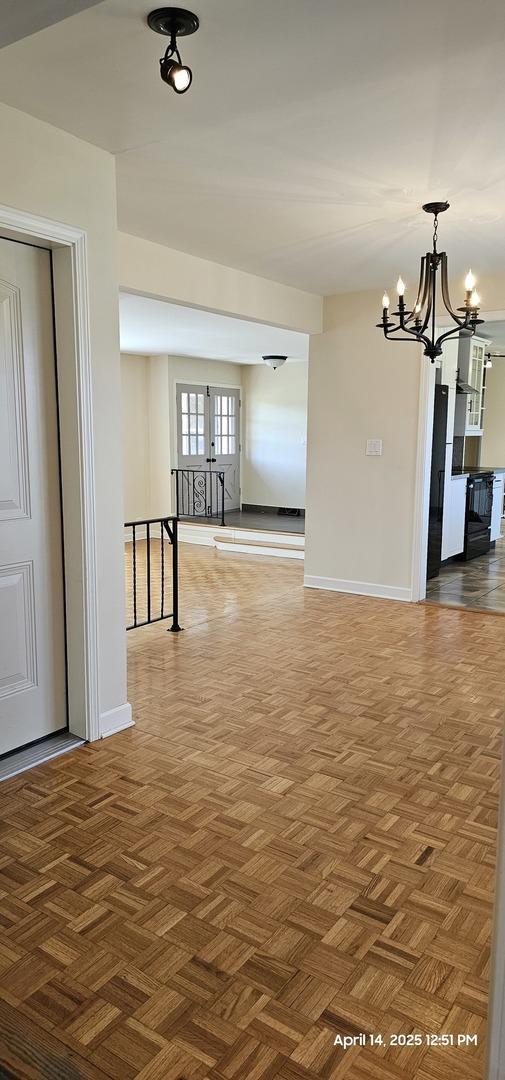 interior space featuring baseboards and a chandelier
