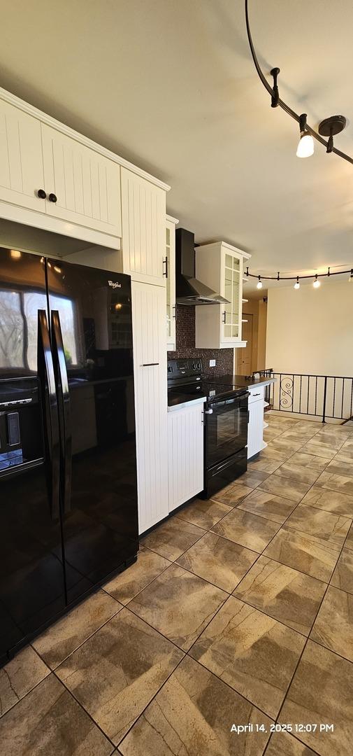 kitchen with white cabinetry, glass insert cabinets, decorative backsplash, wall chimney range hood, and black appliances