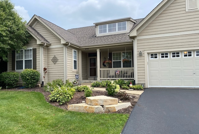 459 E Amberside Dr, Elgin, IL 60124 - view of front facade with covered porch, a shingled roof, asphalt driveway, an attached garage, and a front lawn