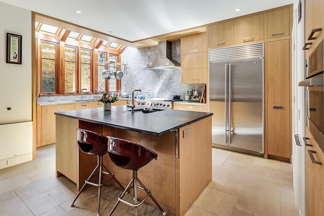 351 W Belden Ave, Chicago, IL 60614 - kitchen featuring wall chimney range hood, backsplash, a center island with sink, stainless steel appliances, and a sink
