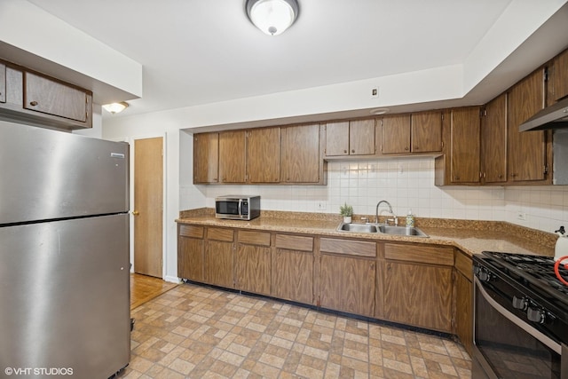 205 Circle Ave Unit 2B, Forest Park, IL 60130 - kitchen with stainless steel appliances, a sink, brown cabinetry, brick patterned flooring, and tasteful backsplash