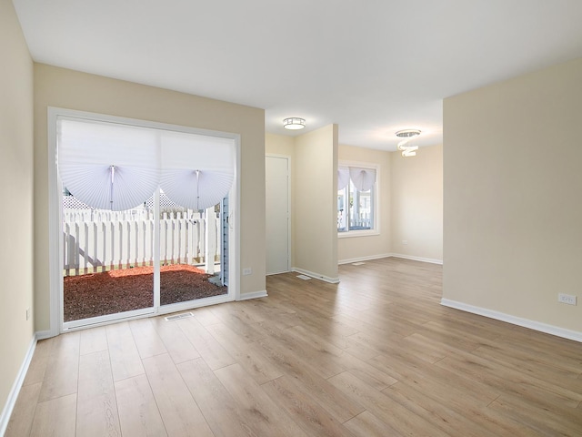 empty room featuring wood finished floors, baseboards, and visible vents