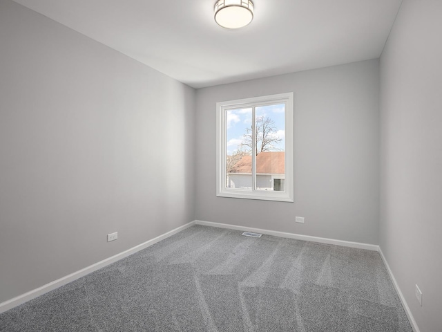 carpeted spare room with visible vents and baseboards