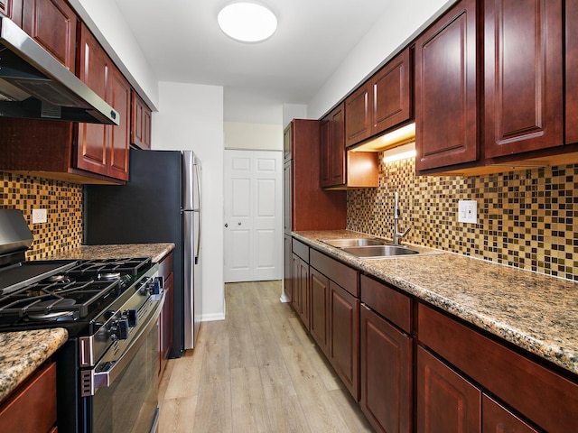 kitchen featuring dark brown cabinets, gas range oven, a sink, and exhaust hood