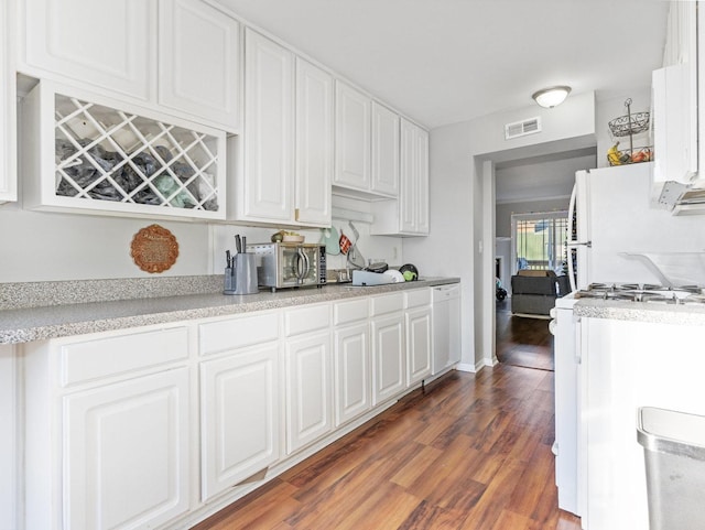 kitchen with white cabinets, visible vents, gas range, light countertops, and dark wood-style floors