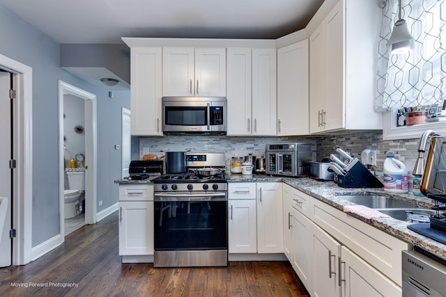 553 E 87th Pl, Chicago, IL 60619 - kitchen with dark wood-style flooring, tasteful backsplash, light stone counters, stainless steel appliances, and white cabinetry