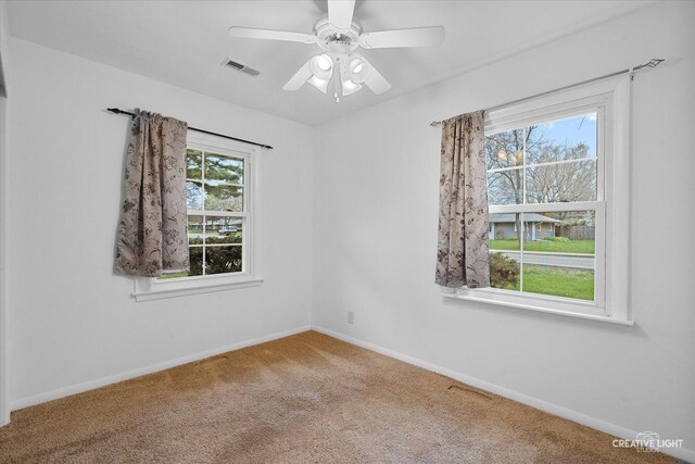 spare room with carpet, visible vents, a ceiling fan, and baseboards