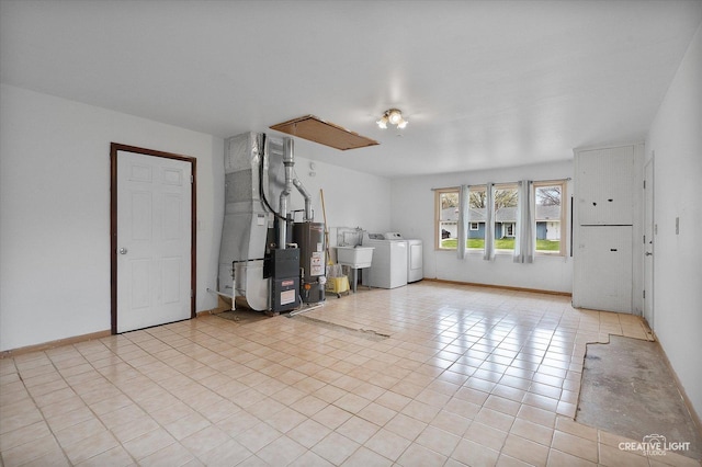 unfurnished living room featuring heating unit, washer and clothes dryer, a sink, gas water heater, and baseboards