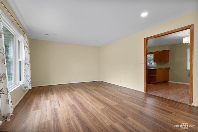 empty room featuring baseboards, a wall mounted AC, and light wood-type flooring