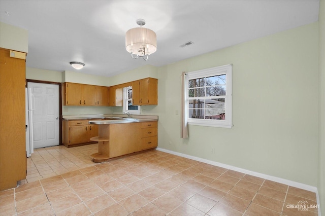 kitchen with light countertops, visible vents, light tile patterned flooring, freestanding refrigerator, and a peninsula