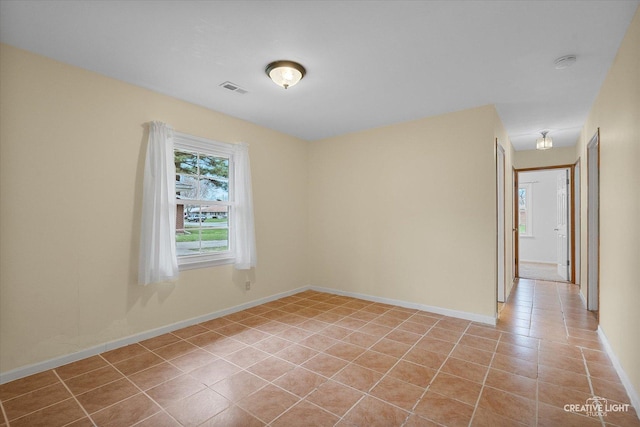 unfurnished room featuring baseboards, visible vents, and light tile patterned floors