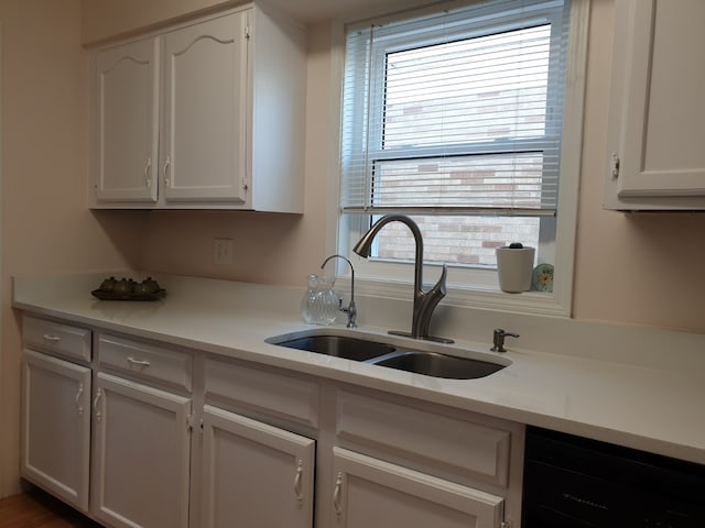kitchen featuring dishwasher, white cabinetry, a sink, and light countertops