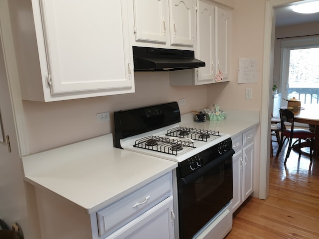 kitchen featuring white cabinets, light wood finished floors, under cabinet range hood, light countertops, and gas range oven