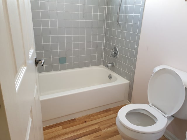 full bath featuring tub / shower combination, wood finished floors, and toilet