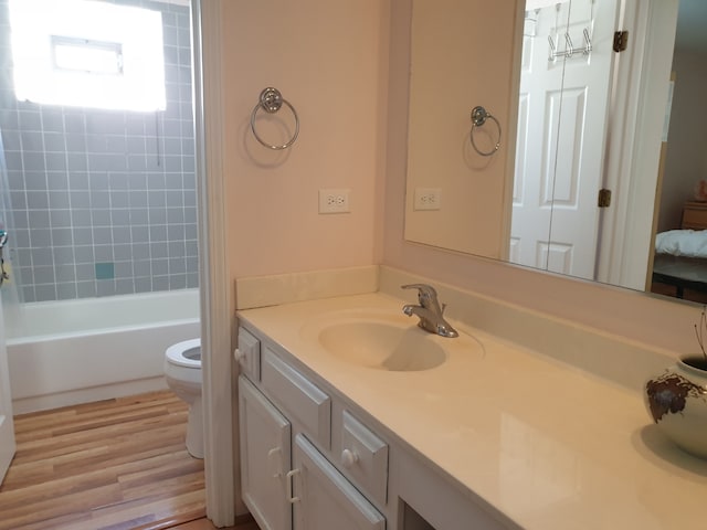 full bath with wood finished floors, toilet, vanity, and bathing tub / shower combination