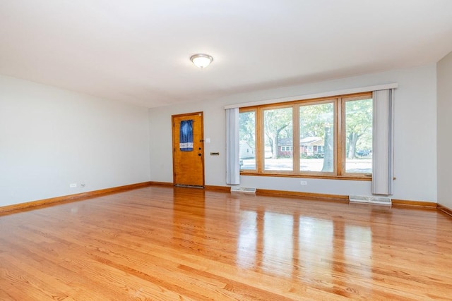 unfurnished living room featuring baseboards, light wood finished floors, and visible vents