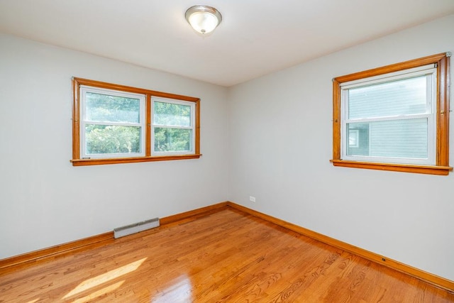spare room with baseboards, light wood finished floors, and visible vents