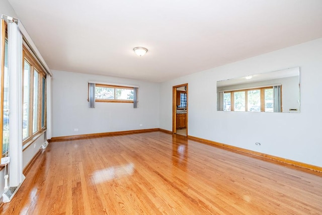 spare room with baseboards and light wood finished floors
