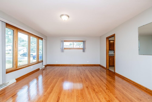 unfurnished room featuring baseboards, visible vents, and light wood-style flooring