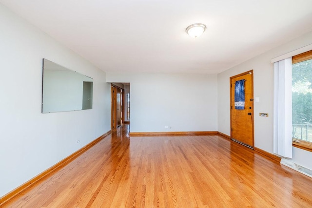 empty room with baseboards and light wood-type flooring