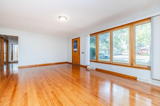 unfurnished living room featuring baseboards, visible vents, and light wood-style floors