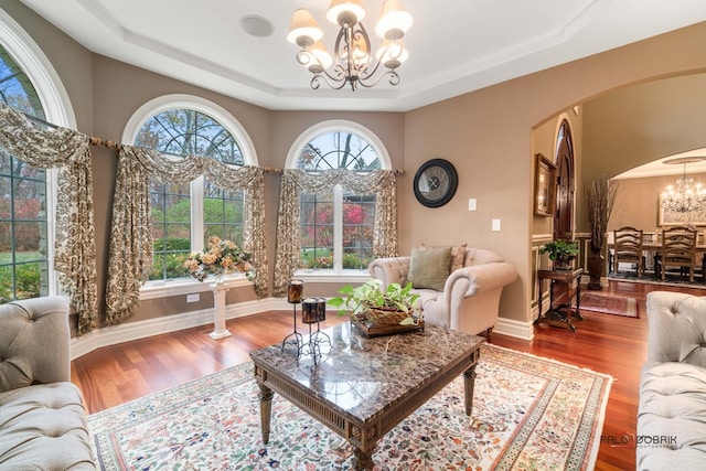 14705 W Mayland Villa Rd, Lincolnshire, IL 60069 - living area featuring a chandelier, a tray ceiling, arched walkways, wood finished floors, and baseboards