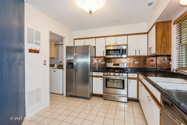 kitchen featuring visible vents, a sink, washing machine and clothes dryer, and stainless steel appliances