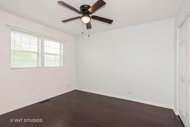 empty room with baseboards, ceiling fan, dark wood-style floors, and visible vents