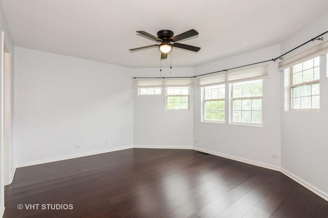 empty room with plenty of natural light, dark wood finished floors, ceiling fan, and visible vents