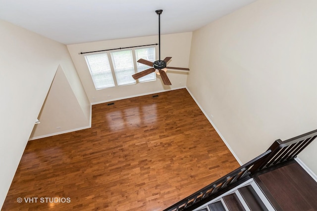 spare room featuring baseboards, ceiling fan, wood finished floors, and visible vents