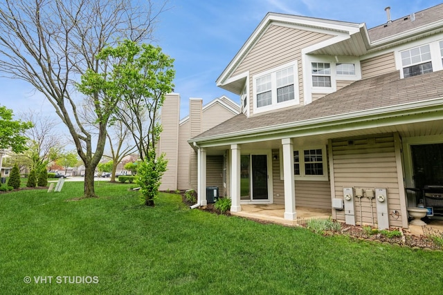 back of house with a patio, a shingled roof, and a yard