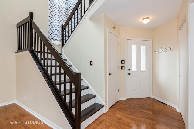 foyer entrance with baseboards, stairs, and wood finished floors