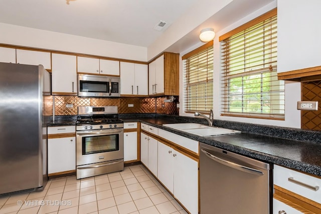 kitchen with a sink, white cabinets, stainless steel appliances, and tasteful backsplash