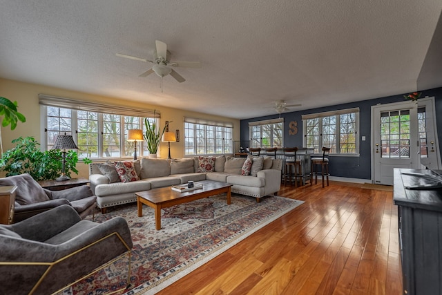 living room featuring light wood-style flooring, a textured ceiling, and ceiling fan
