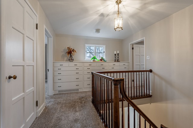 hall featuring dark colored carpet and an upstairs landing